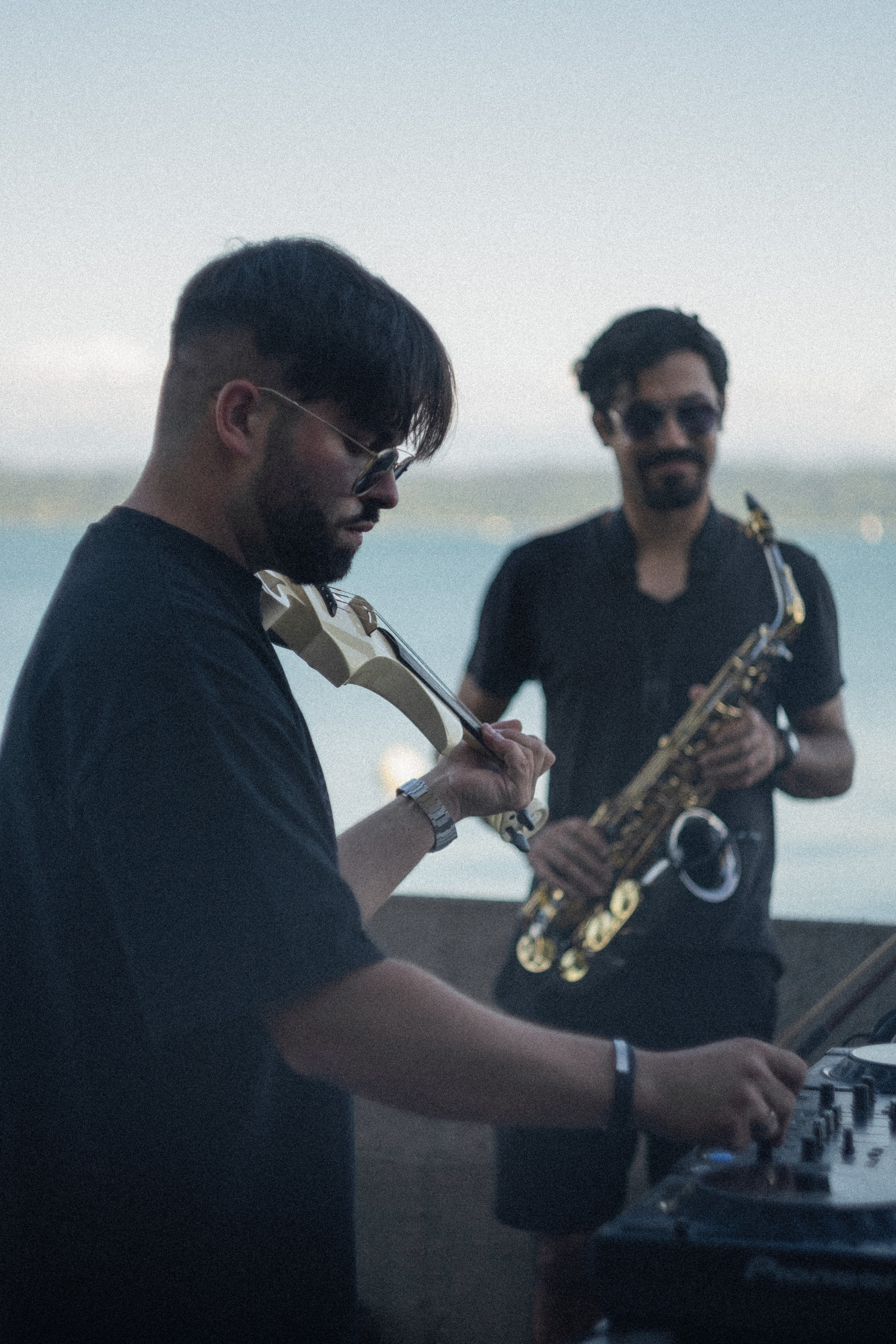 The picture of Dissonance the main DJ of Garden of sound which is playing violin while doing his set and next to him is another musician playing the saxophone